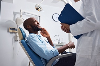 Smiling patient talking to dentist holding clipboard