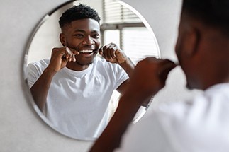 Smiling man flossing his teeth
