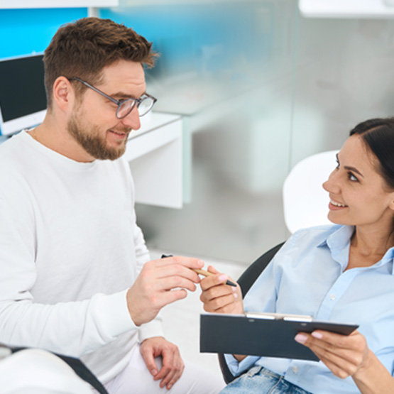 Female patient talking about the cost of dental implants in Rapid City with dental staff member