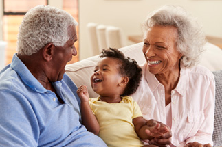 Grandparents on the couch and smiling with their grandchild