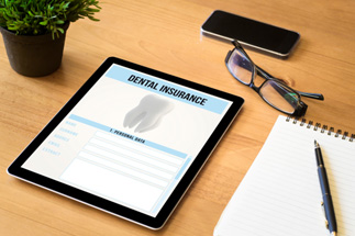 Tablet with dental insurance pulled up and glasses nearby