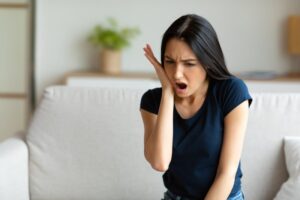 Woman holding jaw in pain.